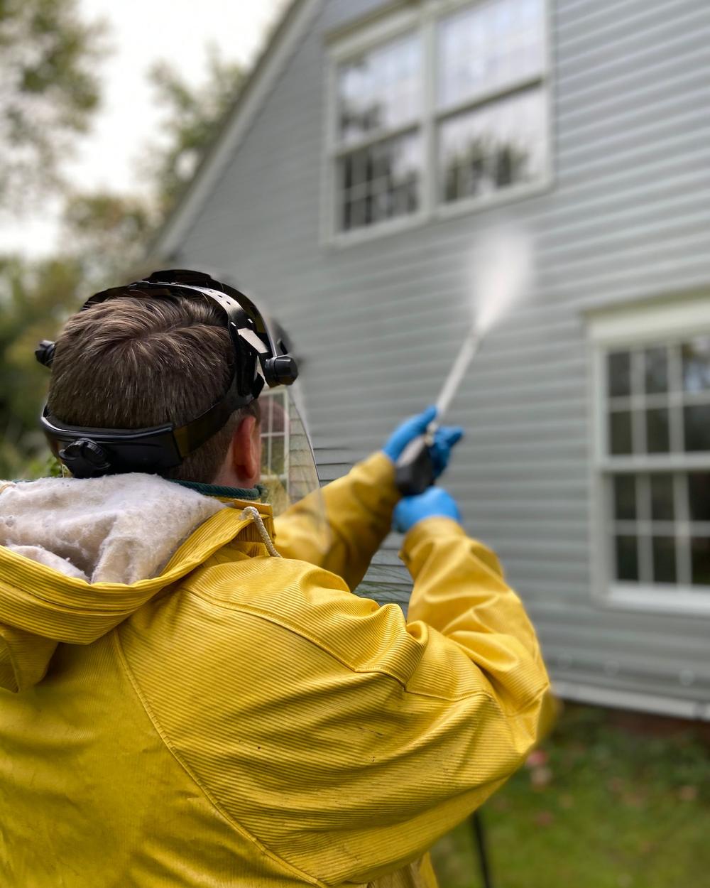 Technician pressure washing a house